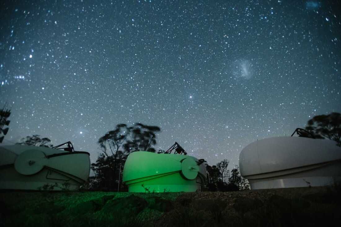 Image of three of the Minerva-Australis telescopes, with the Large and Small Magellanic Clouds overhead.